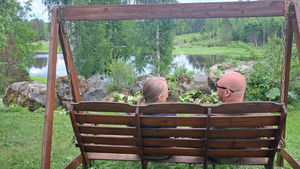 Kaksi henkilöä istumassa pihakeinussa.
